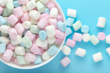 Colorful marshmallows in a bowl on soft blue background