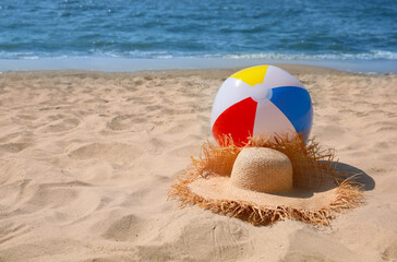 Obraz premium Straw hat and beach ball near sea. Space for text