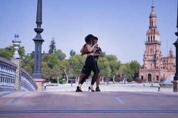 Multi-ethnic young couple doing figures while dancing bachata sensually outdoors. - obrazy, fototapety, plakaty
