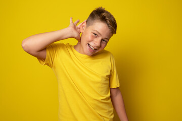 Kid listening something isolated over yellow background.