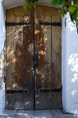 Antique wooden door. On the wall under plaster is a fragment of ancient masonry.