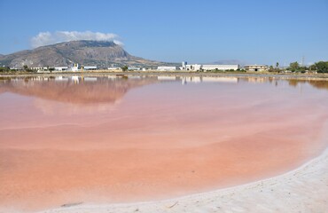 Mount Erice reflects in the red colored waters of Saline di Trapani in Sicily, Italy - obrazy, fototapety, plakaty