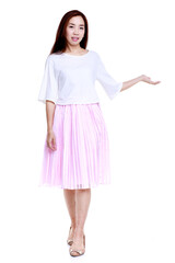 Full body of smiling young Asian female in white blouse and pink skirt pointing with hand aside isolated on white background