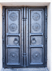 Dark metal doors of the church with carvings. Forged gates of the monastery.