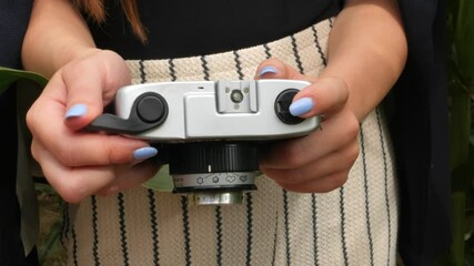 Female photographer holding an old analog film camera and stroke the film advance lever with his thumb
