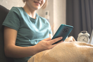 Holiday shopping online, happy young woman makes purchases in the internet in cozy autumn weekends. Girl sitting at home and using mobile phone
