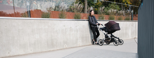 Mother with a pram or stroller on modern city streets walking and relaxing in autumn