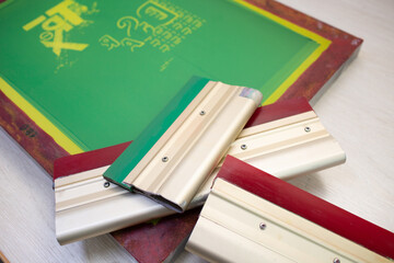 Serigraphy silk screen print process at clothes factory. Frame stencil and squeegee.