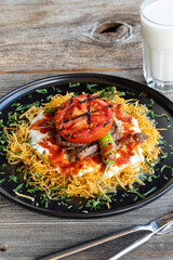 Turkish Cokertme Kebab on a wooden floor. Cokertme kebab is made with grated french fries, yoghurt, tomato sauce and cooked beef.