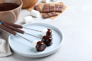 Tasty marshmallows dipped into chocolate on light grey marble table
