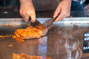 Bougatsa in a shop display, Man cutting pastry in small pieces. Traditional breakfast with cream or...