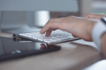 Close up, woman hands typing, working on desktop computer keyboard with digital tablet and mobile phone on table at home office