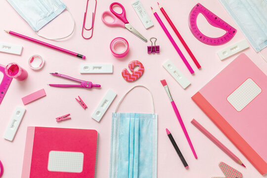 Back to school Covid 19 days. School supplies and Coronavirus measures flat lay. Rapid test, protective medical mask and stationery on pink background