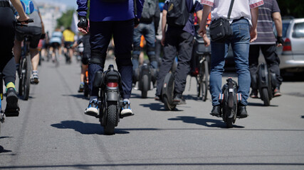 Man riding mono wheel, crowd of people riding bicycles in front of him. Partial view of contestants of street race. Concept of healthy lifestyle © yk_stock
