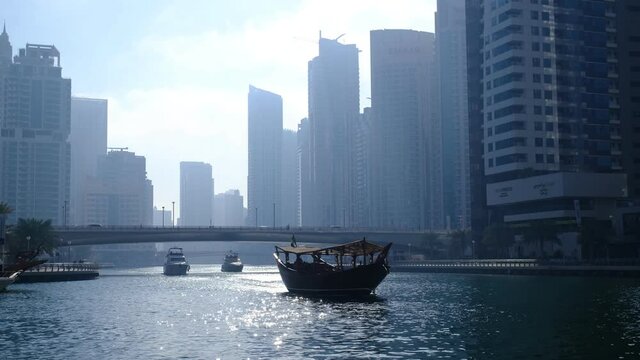 Dubai, UAE, 15.02.2021: Dubai Marina skyline with Marina Canal, modern skyscrapers, luxury hotels and abras boats moving, seen from promenad street