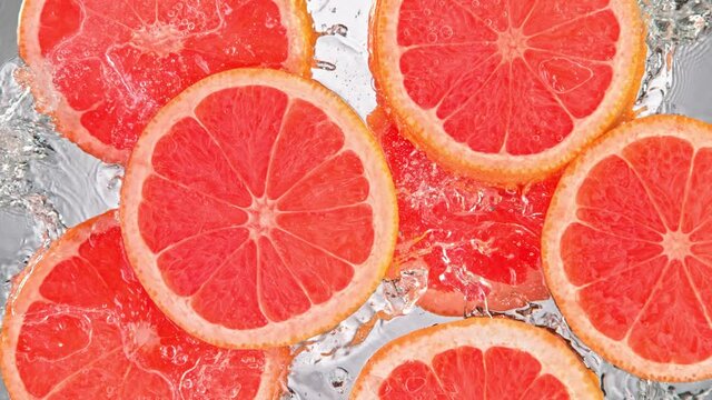 Super Slow Motion Shot of Splashing Fresh Pink Grapefruit Slices into Water at 1000 fps.