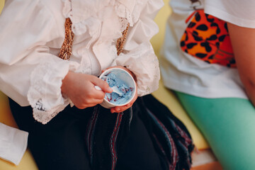 a child in a suit eats lilac ice cream and a cup.