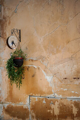 A textured orange wall with cracks and an old clock hanging on it. Background for postcards