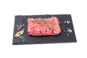 Ground beef, branches of caraway seeds, spices on a stone slate board isolated on a white background.