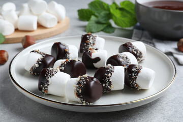 Delicious marshmallows covered with chocolate on light grey table