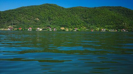Danube river flowing near rural villages and hills. It's blue waters flow slowly with small waves. The hilly region has plenty resorts for a nice summer vacation. Eselnita, Romania.