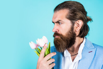 mature bearded male guy looking elegant with spring tulips, summer