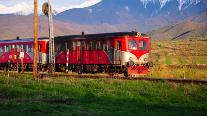 Old train with diesel locomotive transporting passengers along a mountainous, countryside area. Spring season. Eastern Europe, Carpathia, Romania.