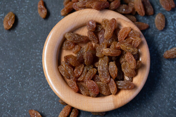 dried green raisins in wooden plate on black background