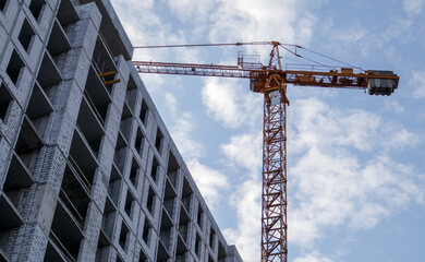 Fototapeta premium Large construction site. The process of capital construction of a high-rise residential complex. Concrete building, construction, industrial site. Industrial crane on the background of the sky.