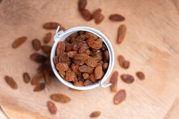 green raisins in a white bucket on the wooden floor