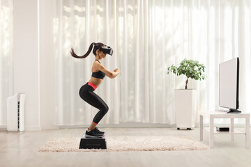 Full length profile shot of a young female exercising on a step aerobic platform with a vr headset