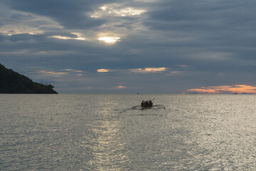 Traditional squid fishermen heading out in their banka boat after the storm for a night's fishing. Oriental Mindoro, The Philippines
