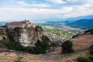 Fototapeta na wymiar ギリシャ　メテオラの断崖絶壁の岩山の上に建つ聖ステファノス修道院と奇岩群の隙間から覗くカランバカの街並み