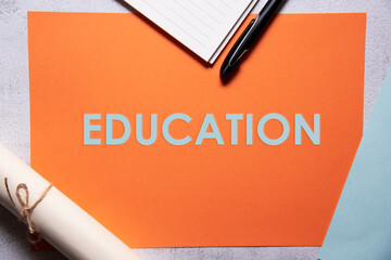 Education text on orange and baby blue background flat lay concept.