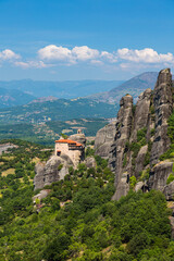 Fototapeta na wymiar ギリシャ　メテオラの断崖絶壁の岩山の上に建つ聖ニコラオス・アナパフサス修道院と後ろに広がる山