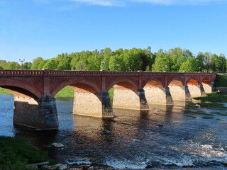 Old red brick bridge over Venta river in Kuldiga - UNESCO World Heritage site, Kurzeme region, Latvia on a beautiful summer day. 