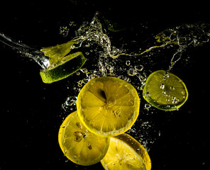 Fototapeta na wymiar Lemon and lime slices dropping in water