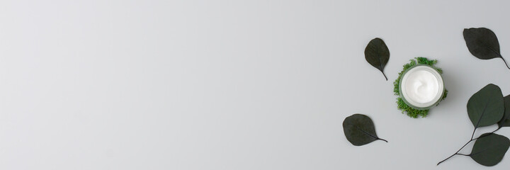 Jar of cosmetic cream with eucalyptus natural background on grey. Flat lay, copy space