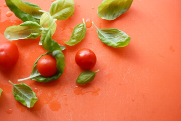 Close-up tomatoes and basil on an orange background. Empty space for text. Flat lay top-down