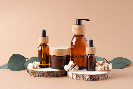 Cosmetic skin care products with eucalyptus and wood on brown background. Close up