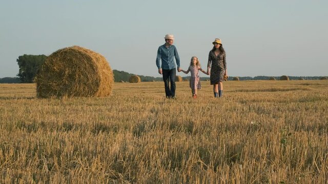 Family of Three Walking in a Harvested Field at Sunset. Slow Motion. Rural Countryside Scenic Landscape