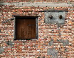 old brick wall of a building with a closed iron window