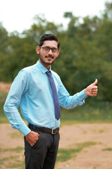 Young indian agronomist giving expresssion over nature background