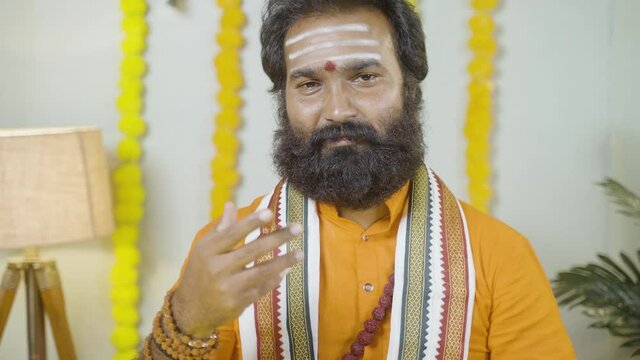 Beard Indian god man or holy guru with rudraksha mala preaching holy vedas by looking into camera - concept of religious teachings by monks or priests at temple
