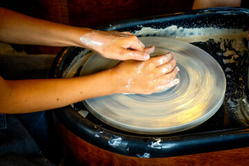 hands of a child on a potter's wheel pottery workshop, clay modeling, children's creativity under the supervision of adults, earlier development of schoolchildren and toddlers