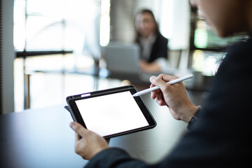 Close-up of an Asian male businessman using a phone with a white blank screen in the office. He uses his cell phone to search, review and save his work.