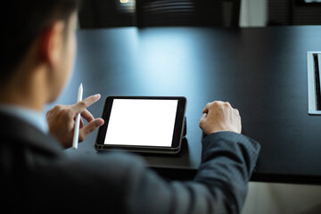 Close-up of an Asian male businessman using a phone with a white blank screen in the office. He uses his cell phone to search, review and save his work.