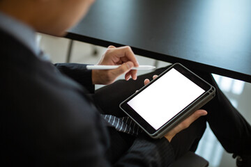 Close-up of an Asian male businessman using a phone with a white blank screen in the office. He uses his cell phone to search, review and save his work.