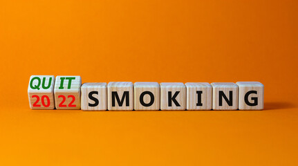 Quit smoking 2022 new years resolution symbol. Turned wooden cubes with words '2022 quit smoking'. Beautiful orange background, copy space. Healthy lifestyle and 2022 quit smoking concept.