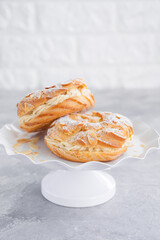 French traditional cake Paris Brest with praline cream, powdered sugar and almond petals on top on a gray concrete background. Copy space.